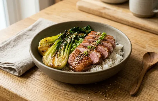 Sliced five-spice duck breast served over jasmine rice with charred pak choi and sesame ginger dressing